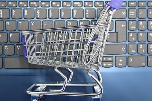 A miniature shopping cart placed on a laptop keyboard symbolizing online shopping and e-commerce.